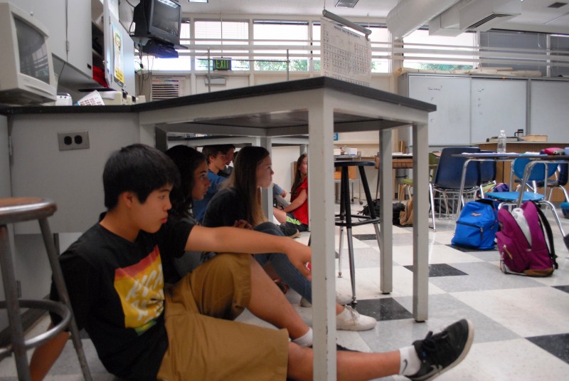 Students huddle under lab tables during the earthquake drill on Oct. 1.