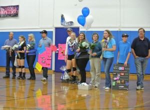 (From left to right) Davis varsity volleyball seniors Mackenzie Harrison, Zoe Hunt-Murray and Jen Blanc stand with their families holding the gifts they have received from JV players and fellow varsity teammates during Senior Night in the South Gym on Nov. 5. They are playing against Elk Grove.