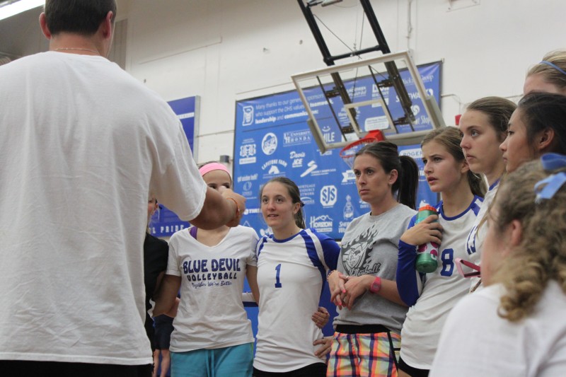 Coach Julie Crawford and the women's varsity volleyball team huddles during a timeout.