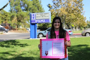 Senior Emily Rogers poses with an educational poster at the front of Holmes Junior High School.