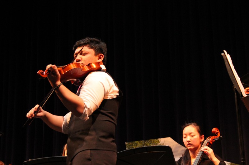 Senior Jazeer Real performs his solo with the baroque ensemble while second chair cellist Becky Yang (right) looks on. 