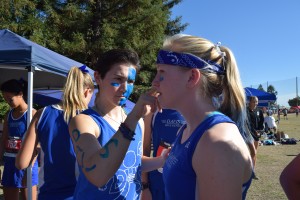 Senior Alex Diaz paints senior Sarah Sherwin’s face before her race.