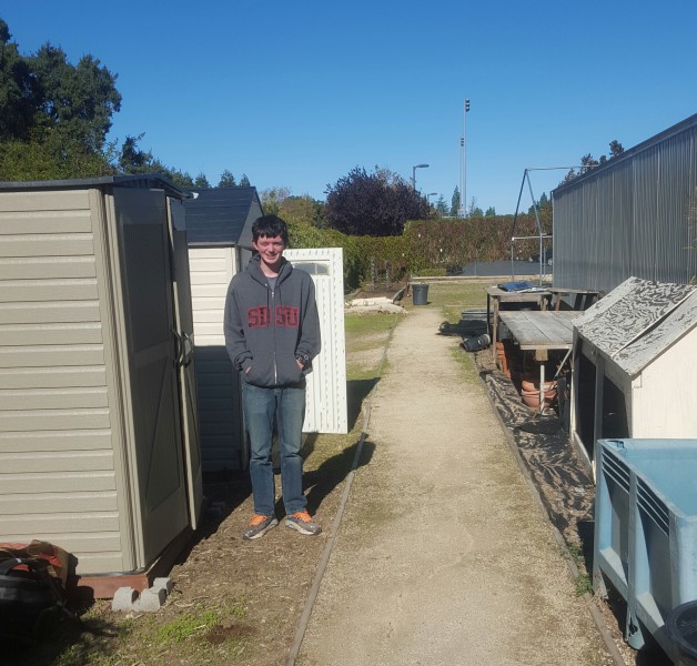 Eagle Scout David Best stands cheerily by a shed he constructed and a clean path once cluttered with weeds. 