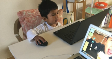 DHS counselor Elizabeth Arroyo's 4-year-old son sitting in front of a laptop with his hand on a mouse