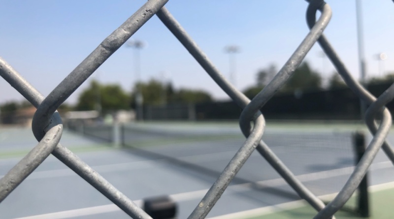 Through the fence, the Davis High tennis courts remain empty