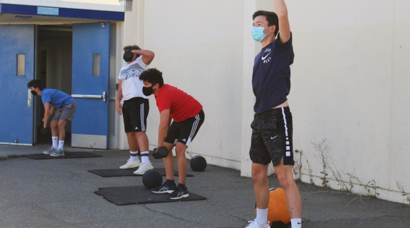 Freshman Alex Gallagher and his water polo team lifting weights in front of the Davis High weight room
