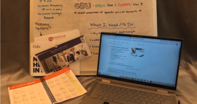 An open laptop and planner splayed out in front of a whiteboard with important dates for the UC and CSU applications