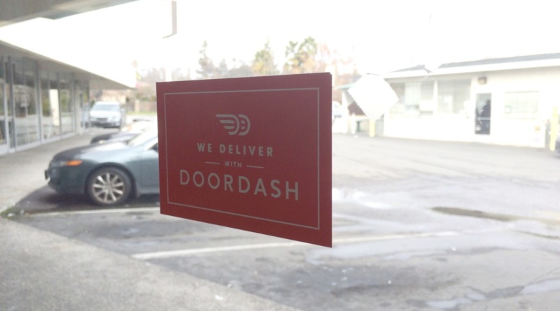 Doordash sign on a window facing a parking lot