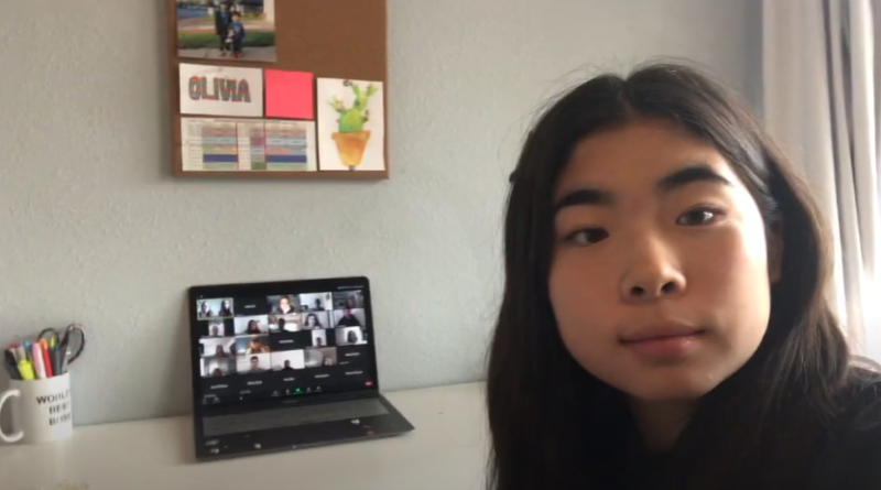 Selfie of Olivia Kim with a Zoom meeting running on a laptop in the background