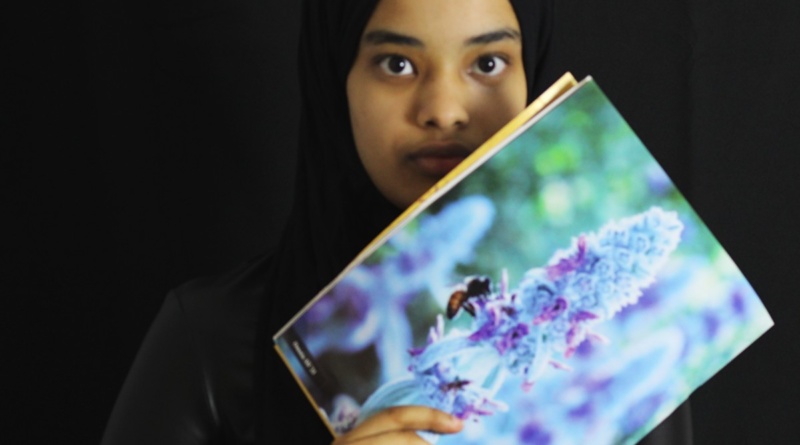 Senior Omnia Ali holding up her previous photography Spoke submissions